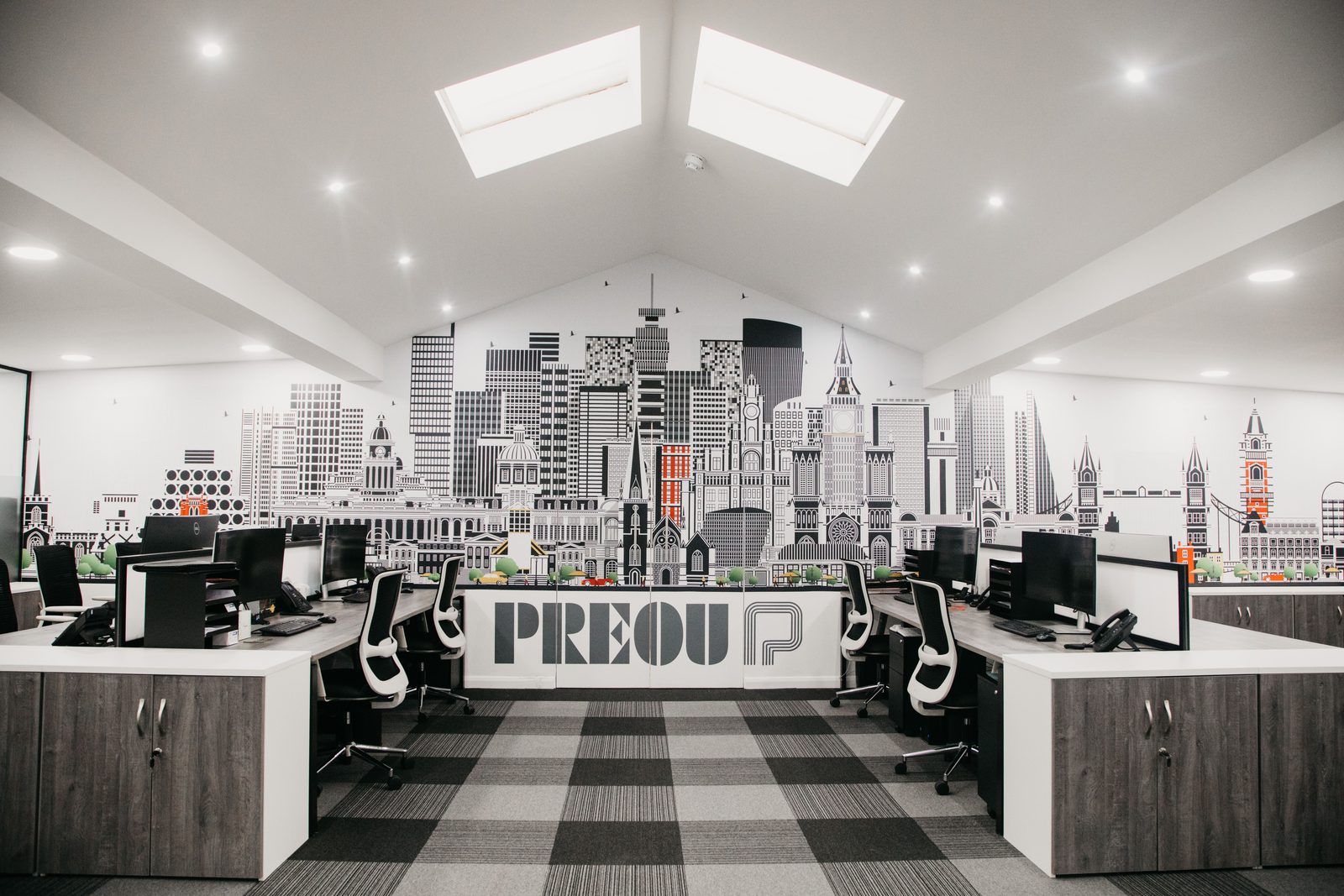 The open plan office at Radford Crescent with a city skyline mural and the Preou logo